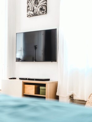 Une chambre à coucher avec un lit, un téléviseur fixé au mur et une table de chevet.