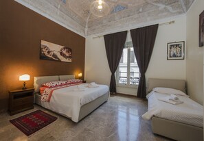 Une chambre d’hôtel avec deux lits, un tapis rouge, un tableau au mur et une fenêtre avec des rideaux.