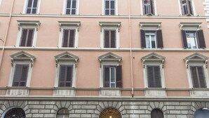 Un bâtiment doté de nombreuses fenêtres et portes, une rue pavée et des voitures garées.