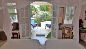 Habitació amb dos llits, vista a la piscina i una cadira a l'exterior.