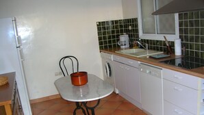 Una cocina pequeña con un refrigerador blanco, un lavamanos, una cafetera y un lavavajillas.