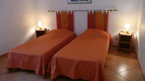 Una habitación con dos camas individuales, cada una con una mesita de noche y una lámpara.