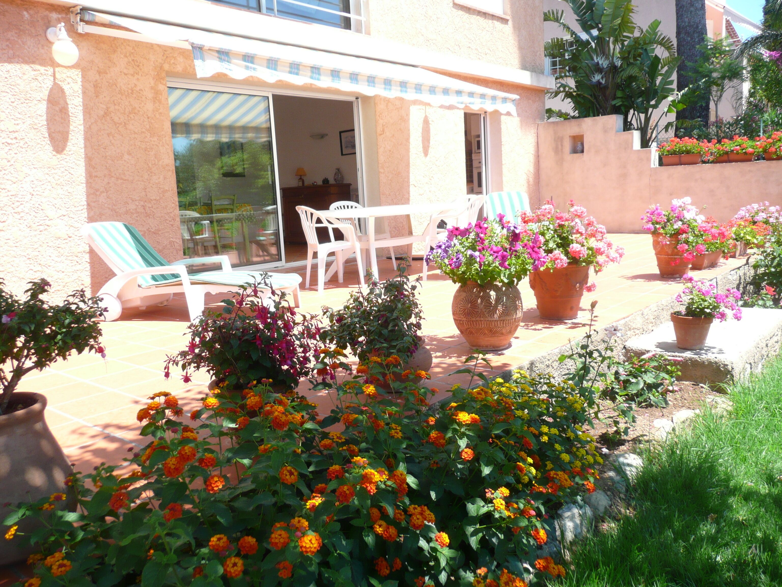 A patio with outdoor furniture, potted plants, and a building entrance.