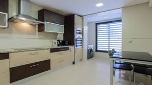 A modern kitchen with a built-in oven, microwave, and coffee maker. There is a dining area with a table and chairs, and a washing machine in the corner. - ★4 Bedroom, Holiday villa with Private Pool, Beach nearby in Albufeira (Albufeira)