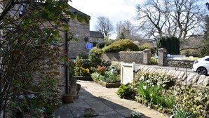 A stone building with a garden in front, a white gate, and a parked car. - Yorkshire Dales Stone Cottage. Wonderful Location for Walking in Swaledale (Grinton)