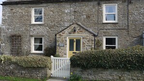 A stone house with a yellow door, a white gate, and a sign reading "Corner House". - Yorkshire Dales Stone Cottage. Wonderful Location for Walking in Swaledale (Grinton)