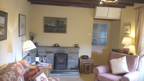 A cozy living room with a fireplace, a sofa, a chair, and a small table with a lamp. - Yorkshire Dales Stone Cottage. Wonderful Location for Walking in Swaledale (Grinton)
