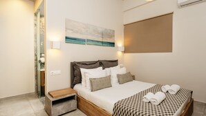 A bedroom with a bed, bedside tables, a wall-mounted air conditioner, and a window with a blind. - Eumelia Iconic Villa, with Heated Pool & Whirlpool, BBQ, Close to amenities (Rethymno)