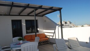Une terrasse sur le toit équipée d’une table, de chaises, d’un canapé et de deux chaises longues.
