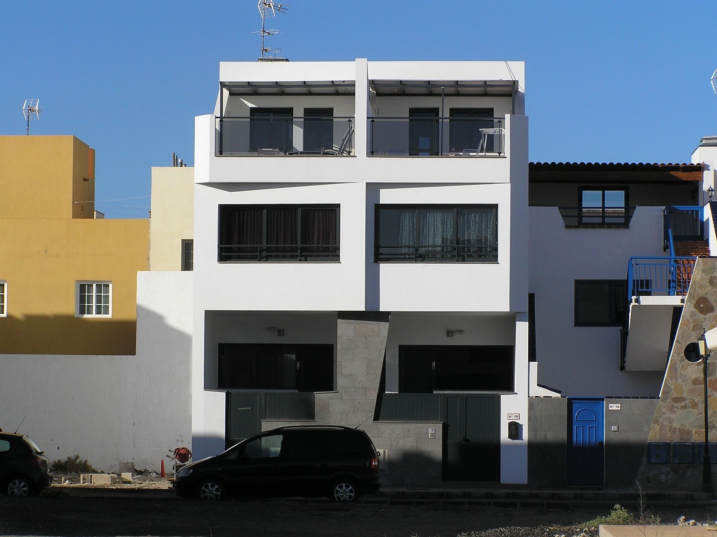 Un bâtiment moderne à deux étages, doté d’un toit plat, de grandes fenêtres et d’un balcon à l’étage supérieur.
