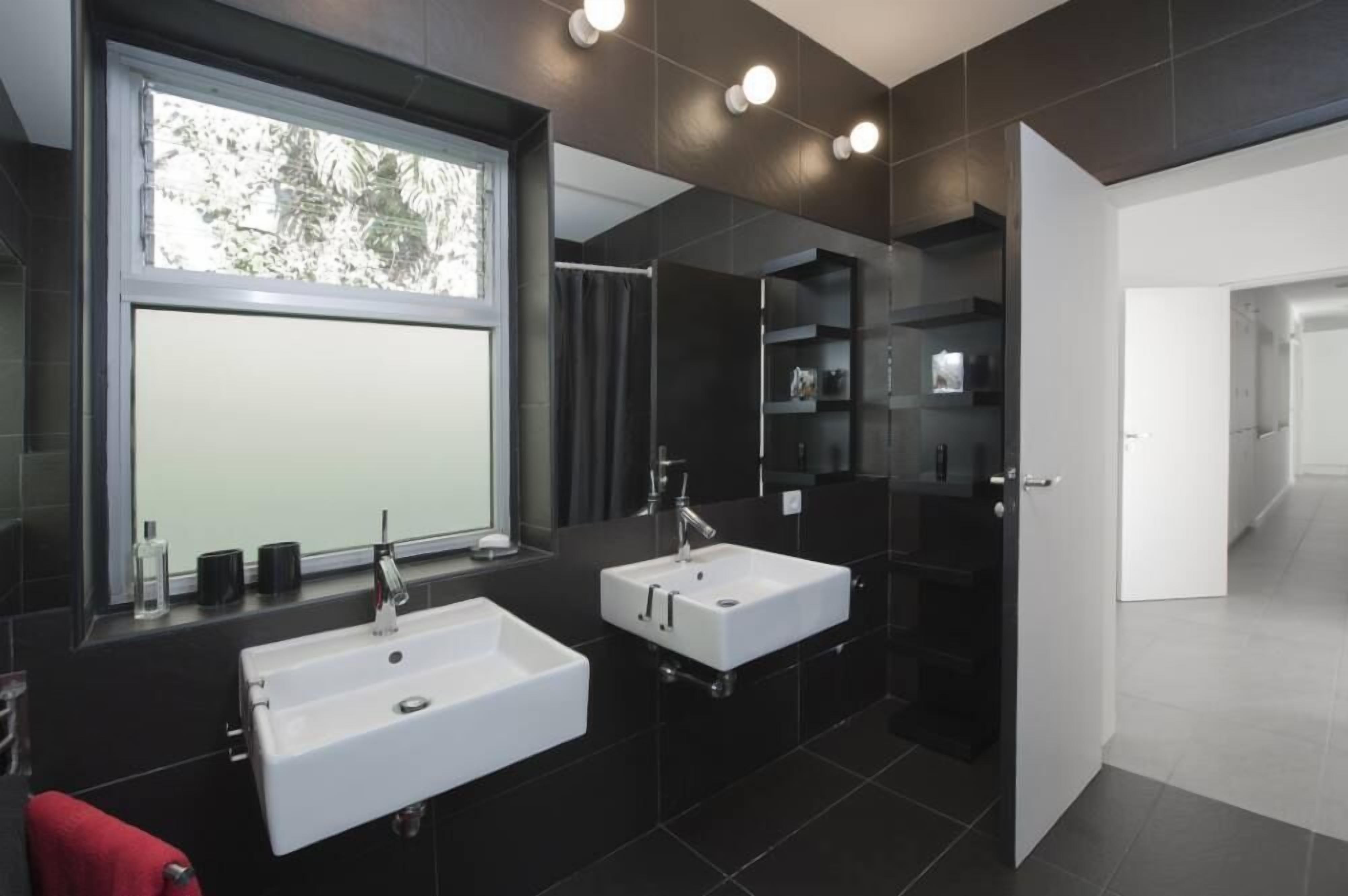 Ein modernes Badezimmer mit zwei Waschbecken, einem großen Spiegel und einem Fenster.