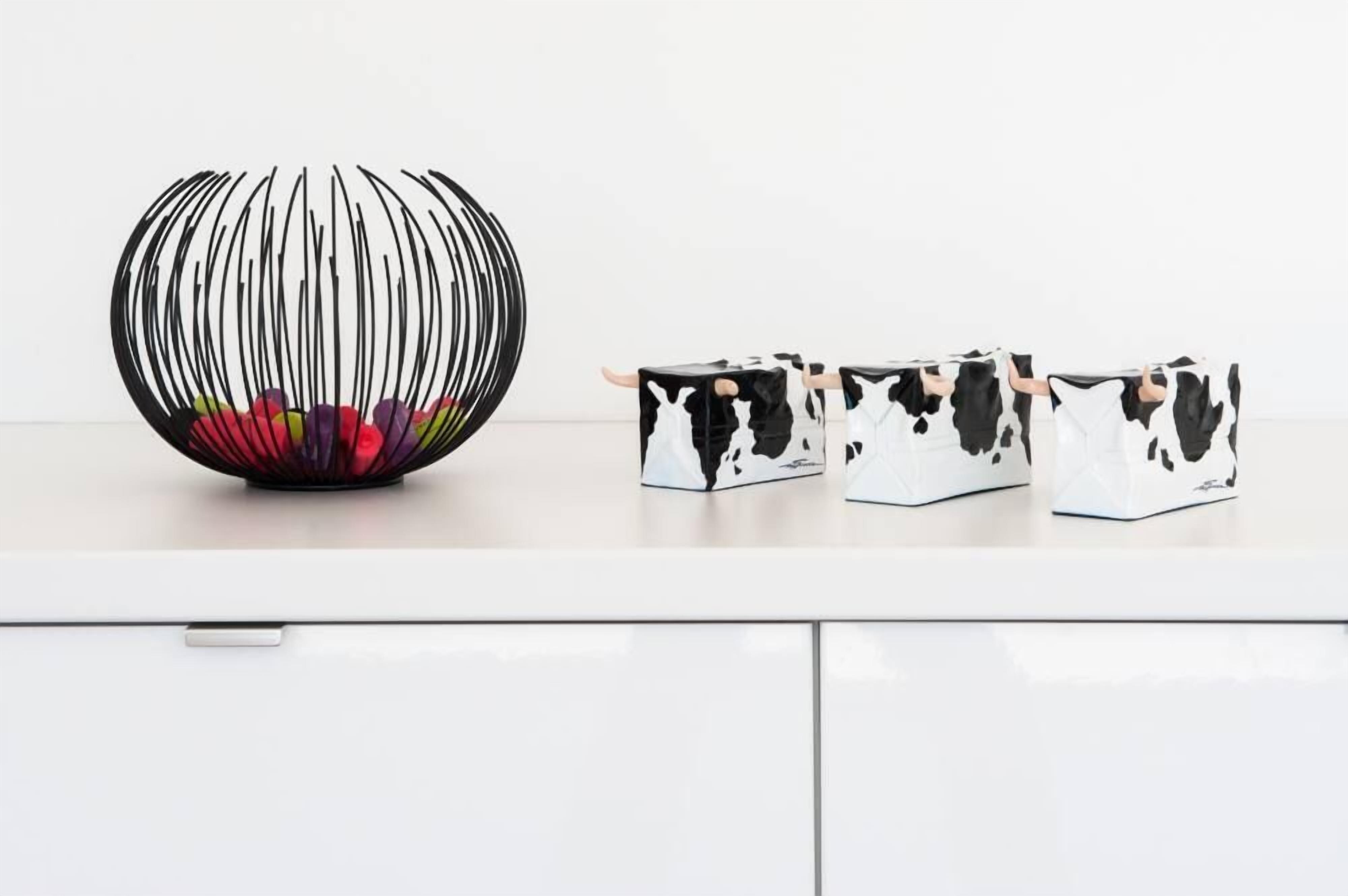 A white cabinet with three storage boxes and a decorative spherical object.