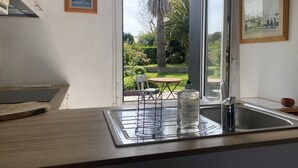 Une cuisine avec une fenêtre, un évier et une table avec des chaises.