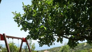Un parque infantil con columpios, toboganes y un juego con forma de barco azul, frente a un cielo despejado y colinas lejanas.