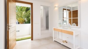 Une salle de bain moderne avec un meuble-lavabo blanc, un grand miroir et une petite fenêtre.