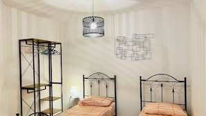 A bedroom with two single beds, a hanging light fixture, a wall-mounted abstract art piece, and a metal shelving unit. - GORGEOUS PENTHOUSE WITH SEA VIEW GIUSI BREATHTAKING ... FREE WIFI INTERNET !!! (Balestrate)