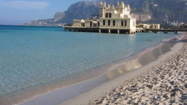 A beachfront building with a balcony overlooking the sea, a pier extending into the water, and a mountainous backdrop. - GORGEOUS PENTHOUSE WITH SEA VIEW GIUSI BREATHTAKING ... FREE WIFI INTERNET !!! (Balestrate)