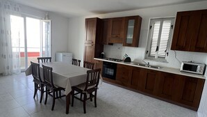A modern kitchen with wooden cabinets, a dining table with chairs, and a large window. - GORGEOUS PENTHOUSE WITH SEA VIEW GIUSI BREATHTAKING ... FREE WIFI INTERNET !!! (Balestrate)