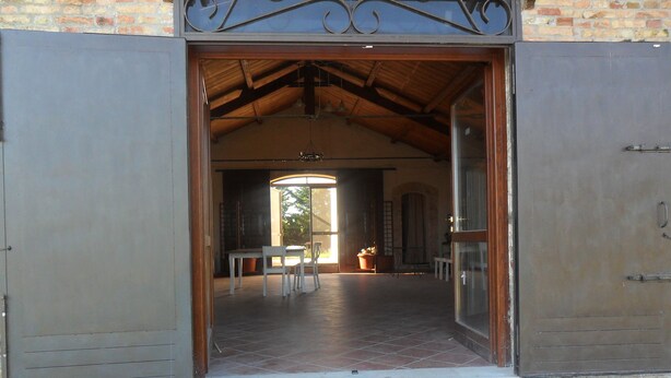 Una puerta abierta que da a un espacio interior con piso de baldosas, una mesa y sillas.