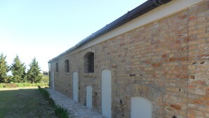 Un edificio largo y estrecho con fachada de ladrillo y un camino empedrado de piedra que lleva hacia él.