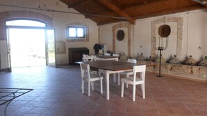 Un comedor amplio con una mesa de madera y sillas blancas, una chimenea y vistas al exterior.