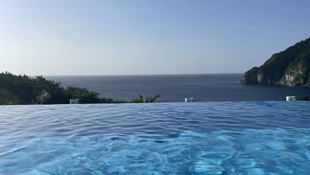A clear view of a swimming pool with a view of the ocean and a cliff. - SEA VIEW VILLA + OVERFLOW POOL (Deshaies)