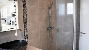 Un baño con un lavabo de piedra, ducha y pared con azulejos.