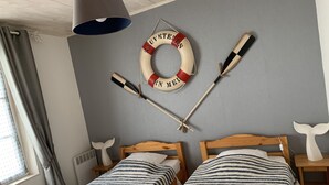 Una habitación con dos camas de madera, un flotador, dos remos y una lámpara.