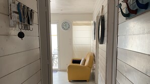 Un pasillo con paredes de madera blanca, un sillón amarillo y un reloj en la pared.