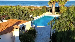 A swimming pool with a view of the ocean, surrounded by greenery and a stone pathway. - Villa with swimming pool facing the sea, for those who love peace and privacy (Marzamemi (Pachino) -SR)