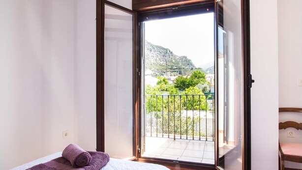 A hotel room with a bed, a window with a view of a balcony, and a chair. - house with pool, barbecue (Nigüelas)