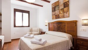 A bedroom with a large bed, a chair, a nightstand, a wall art piece, and a window. - house with pool, barbecue (Nigüelas)