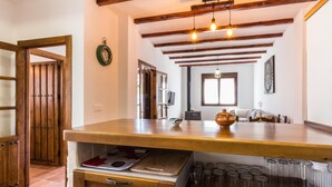 A kitchen with wooden beams, a large island with a sink, and a window with natural light. - house with pool, barbecue (Nigüelas)