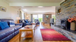 A modern living room with a stone fireplace, leather sofa, and a television.