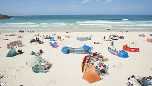 A beach with tents, umbrellas, and people relaxing.