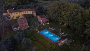 Vue aérienne d’un vaste domaine comprenant une piscine, plusieurs bâtiments et une végétation luxuriante.