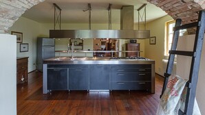 Une cuisine dotée d’un îlot central, d’appareils électroménagers en acier inoxydable et d’une arche en briques.