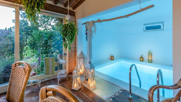 Une salle de spa moderne dotée d’une grande baignoire, de fauteuils en osier, de plantes suspendues et de lanternes décoratives.