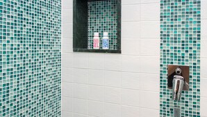 A shower area with a tiled wall, a small shelf with toiletries, and a showerhead. - DOMUS VIGNA Fusco, AMALFI COAST (FURORE (SA))