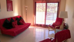 Una sala de estar con un sofá rojo, un sillón rojo y una lámpara de pie.