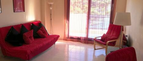 Un salon avec un canapé rouge, un fauteuil rouge et un lampadaire.