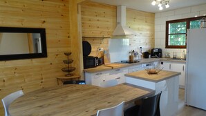 A modern kitchen with wooden walls, a central island with chairs, and a dining table. - In Mimizan-plage sud, detached house with fenced garden, 2km from beaches (Mimizan)