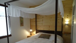 A single bed with a canopy, a bedside lamp, and a wooden headboard in a room with a wooden wall. - In Mimizan-plage sud, detached house with fenced garden, 2km from beaches (Mimizan)
