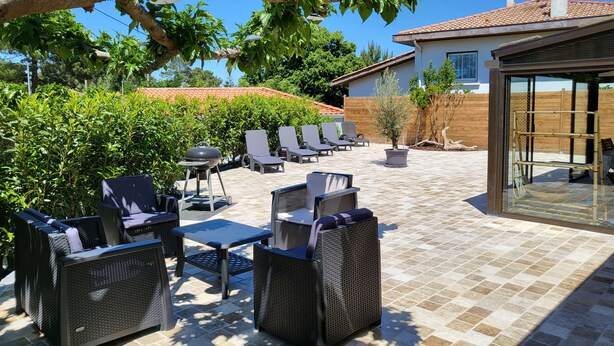 An outdoor patio with wicker furniture, a grill, and a view of a house with a tiled roof. - In Mimizan-plage sud, detached house with fenced garden, 2km from beaches (Mimizan)