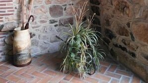 Un muro de piedra con un letrero de madera, un farol y una planta en maceta.