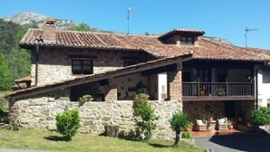 Una casa de piedra con techo inclinado, un balcón y un pequeño porche.
