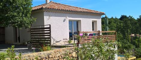 A white building with a tiled roof, a stone wall in front, and a wooden fence.