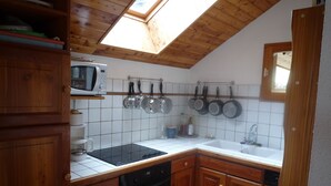 Une cuisine avec des meubles en bois, un four à micro-ondes, une cuisinière, un évier et une lucarne.
