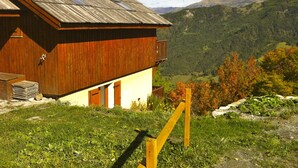 Une cabane en bois dotée d’un balcon, située dans un cadre montagneux.