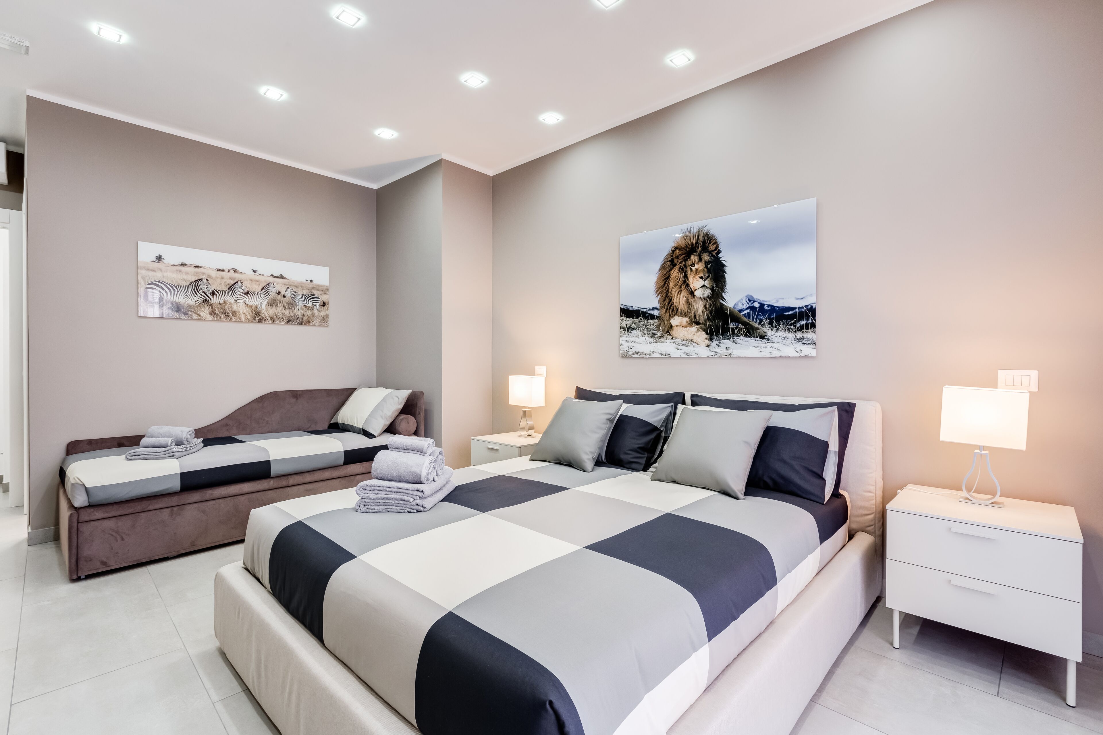 Un dormitorio moderno con una cama grande, dos mesitas de noche y obras de arte en las paredes.